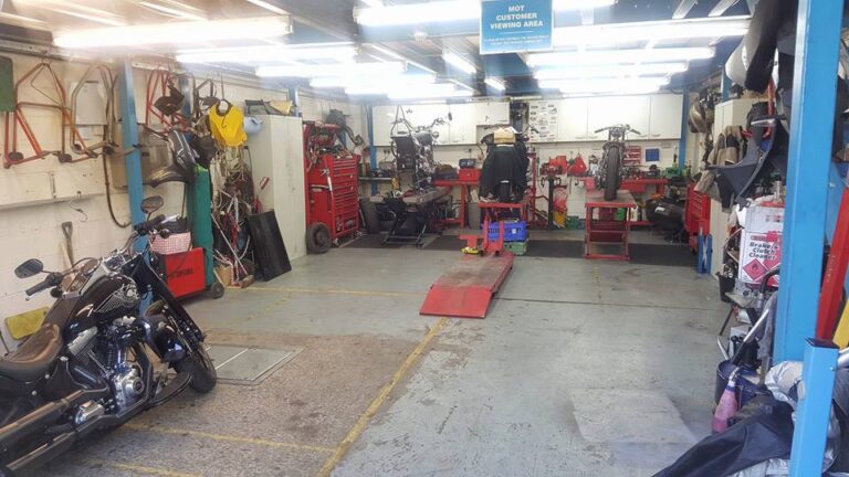 An organized and well-lit motorcycle workshop with neatly arranged tools, workbenches, and motorcycles awaiting maintenance or customization.